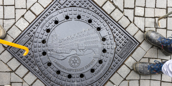 auf einem Gullideckel ist die Erfurter Krämerbrücke abgebildet